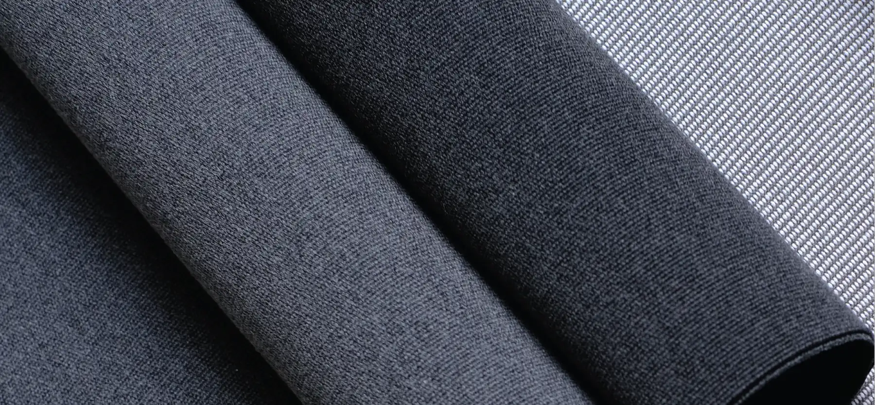 Rolls of Ateja Sunproof outdoor fabric in charcoal, grey and black, supplied by Urban Maisons in Malaysia